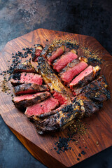 Modern style traditional barbecue dry aged wagyu porterhouse beef steak bistecca alla Fiorentina sliced and served as close-up on a wooden design board
