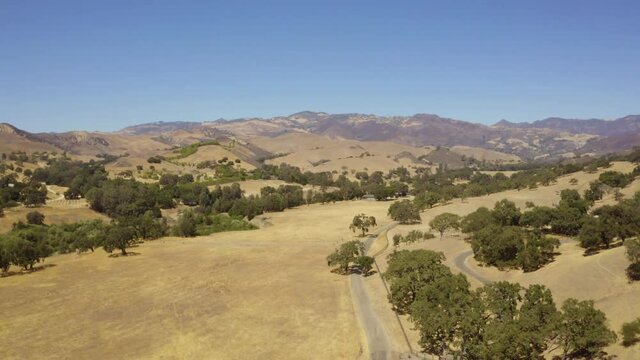 Beautiful outdoor ranch landscape, vast golden mountain tops with long views of valleys and oak trees and incredible rolling hillsides all seen from an aerial view of California's most serene vistas.