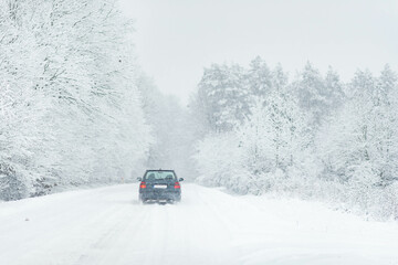 Car driving  after heavy snowfall, transportation in winter, road covered in snow,  weather problems, driving through winter forest