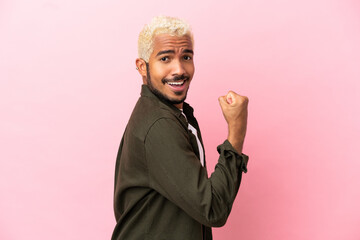 Young Colombian handsome man isolated on pink background doing strong gesture