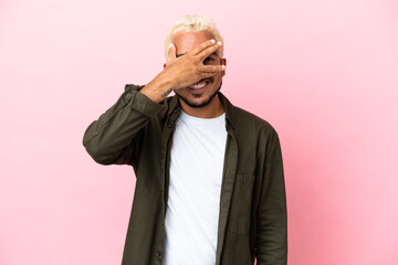 Young Colombian handsome man isolated on pink background covering eyes by hands and smiling
