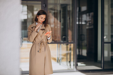 Young beautiful woman wearing coat walking in the city and talking on the phone