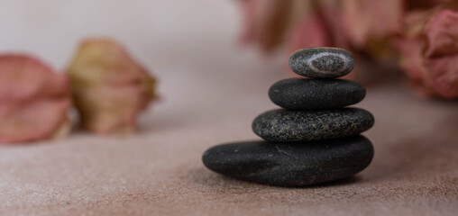 Banner. Pyramids of gray zen pebble meditation stones with green leaves on beige background. Concept of harmony, balance and meditation, spa, massage, relax.