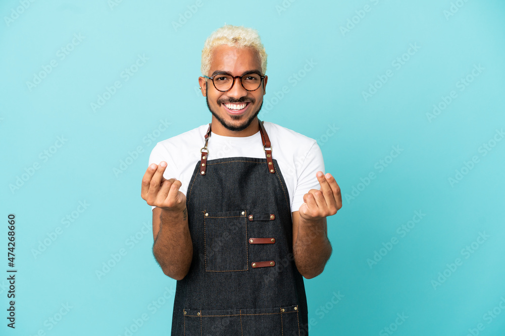 Wall mural restaurant colombian waiter man isolated on blue background making money gesture