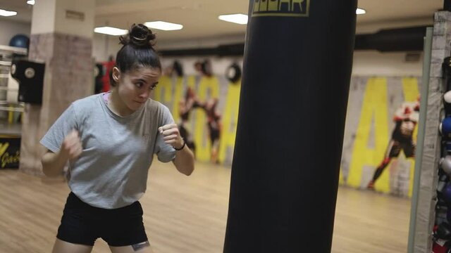 a young girl hits a punching bag to train for a competition.