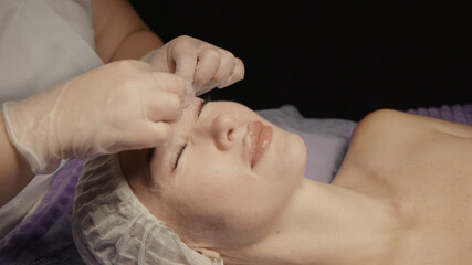 Obraz na płótnie Canvas Woman receiving facial massage in spa salon on massage table. Wellness body and skin care, face beauty treatment, receiving rejuvenation procedure