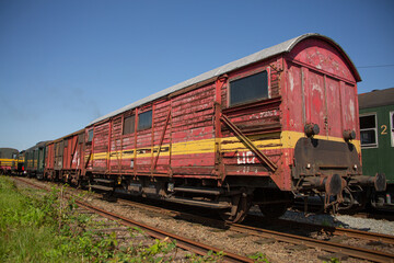 Fototapeta na wymiar Weathered old wooden train carriage with yellow stripe on the side parked on railway tracks