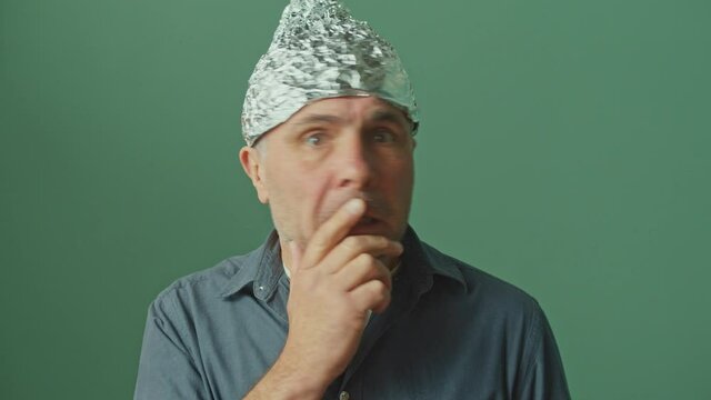 A Paranoid Man with a Protective Foil Cap on his Head Looks Around Anxiously, Looks Frightened and Shocked. Fear Of 5G Waves, Electromagnetic Fields, Mind Control, Mind Reading, Global Conspiracy.
