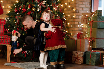 Fototapeta na wymiar Father and little child having fun and playing together at home. Portrait loving family close up. Cheerful dad with cute baby daughter girl near Christmas tree. Merry Christmas and Happy Holidays.