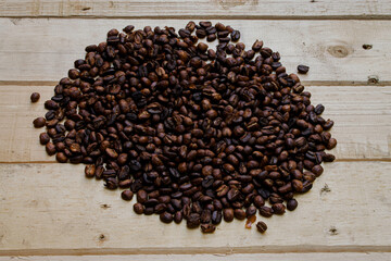 Granos de caf&eacute; tostados sobre madera.