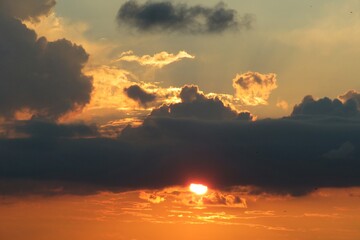 Beautiful orange sunset with long black dramatic cloud in the sky