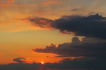 Beautiful orange sunset with dark dramatic clouds in the sky