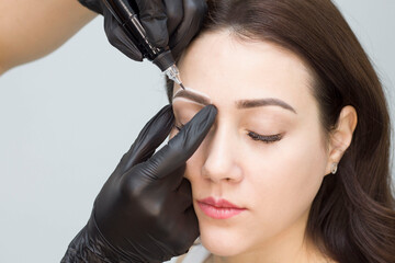 Permanent eyebrow makeup. The girl in the salon is doing permanent makeup. Tattooing. A girl in a beauty salon.