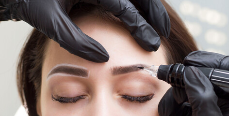 Permanent eyebrow makeup. The girl in the salon is doing permanent makeup. Tattooing. A girl in a beauty salon.