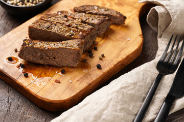 A piece of cooked beef meat steak on wooden board cut in slices