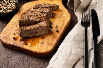 A piece of cooked beef meat steak on wooden board cut in slices