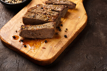 A piece of cooked beef meat steak on wooden board cut in slices