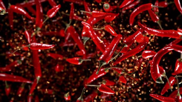 Super slow motion of flying red hot chilli peppers isolated on black background. Overhead view, filmed on high speed cinema camera, 1000 fps. Ultimate perspective of flying food. Speed ramp effect.
