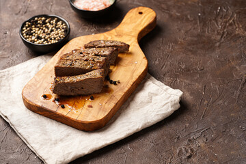 A piece of cooked beef meat steak on wooden board cut in slices, white and black peer, coarse sea salt