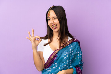 Young Indian woman isolated on purple background showing ok sign with fingers