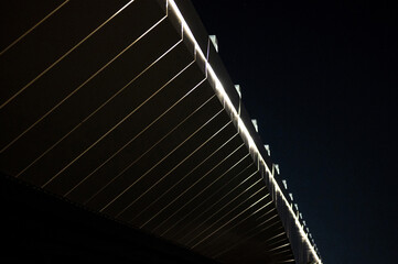 Architectural elements of a metal and concrete bridge with night sky in background.