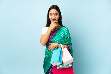 Young Indian woman with shopping bags thinking