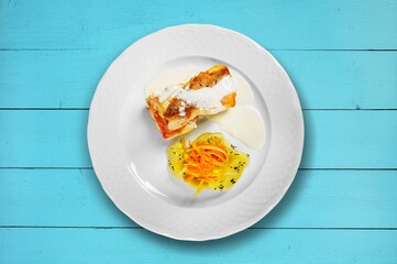 Plate of fried fish fillet with vegetables on the desk