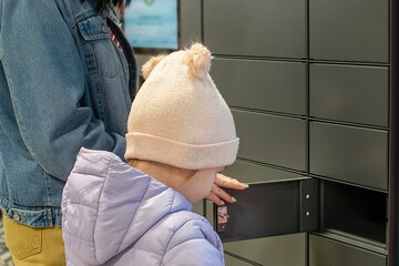 Mom and daughter receive their order, their purchases over the Internet in a self-service postal...