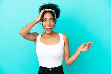 Young latin woman isolated on blue background surprised and pointing finger to the side