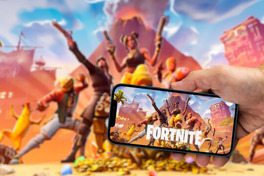 Male hand holding a smartphone with Fortnite Season 8 mobile app on the smartphone screen with the game blurred in the background. Rio de Janeiro, RJ, Brazil. December 2021