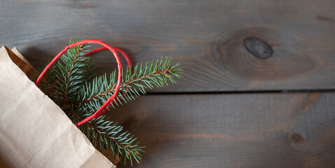 Fototapeta na wymiar fir branch in the eco paper bag on the wooden background Copy space for christmas ideas