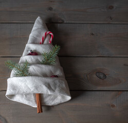folded old napkin in the shape of a fir tree , decorated with some christmas decorations.