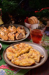 Obraz na płótnie Canvas Small pizza with brie cheese and nuts on a plate. Meat pies on a plate. Tea with viburnum in a glass cup. Jam, cookies. New Year's napkin.