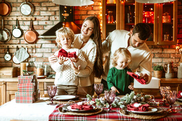 family of four parents pregnant mom and dad and two siblings little boy and girl in stylish clothes in chalet are ready to welcome Christmas and New Year at set table for festive dinner