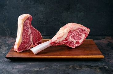 Two raw dry aged wagyu porterhouse and tomahawk beef steaks offered as close-up on modern design...