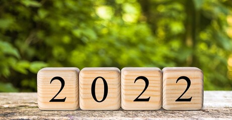 Happy New Year 2022 on wood cube block and nature background