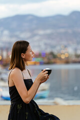 Tranquil day serene woman relaxing drinking coffee enjoying ocean sea view on water and mountains, summer travel holidays.