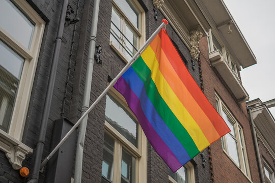Gay flag in Amsterdam. Gay rainbow flag on a building. Rainbow flag of the LGBT community on the building on street Amsterdam. 
