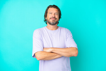 Senior dutch man isolated on blue background keeping the arms crossed in frontal position
