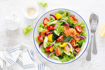 Salted salmon salad with fresh green lettuce, cucumbers, tomato, bell pepper and red onion....