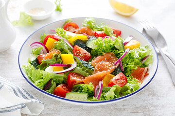 Salted salmon salad with fresh green lettuce, cucumbers, tomato, bell pepper and red onion. Ketogenic, keto or paleo diet lunch bowl - obrazy, fototapety, plakaty