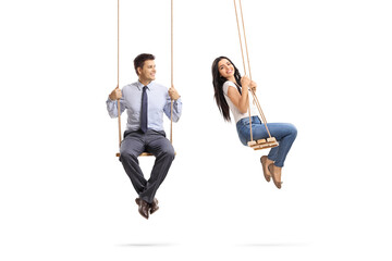Man sitting on a swing and looking at a beautiful young woman swinging - obrazy, fototapety, plakaty