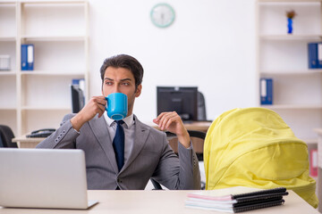 Young male employee looking after new born at workplace