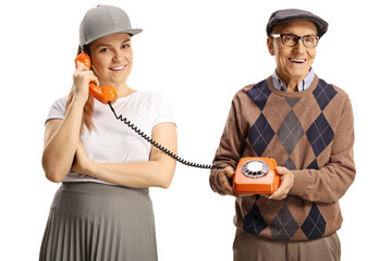 Elderly man holding a vintage rotary phone and a young female talking