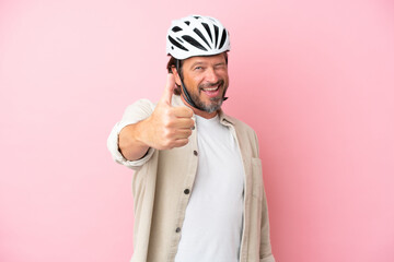 Senior dutch man with bike helmet isolated on pink background with thumbs up because something good has happened