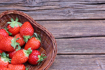 古い木材背景の籠にいれたイチゴ