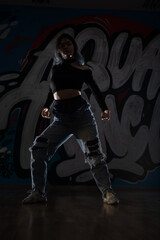 Female dancer in activewear squatting on the floor of modern dance studio and looking at you