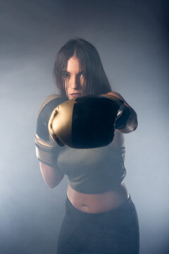 Foggy image of a young and sexy female boxer punching direct hit with boxing gloves