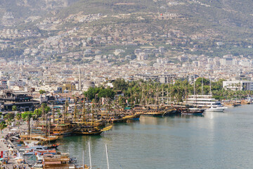 Naklejka premium Alanya, Turkey - 24 July 2021: Sea pier port for yachts and boats in marina on a background of mountainous terrain. Sea coast