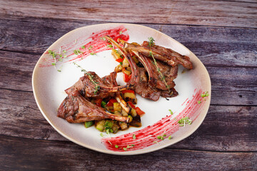 Spicy hot fried spare ribs on a plate against the background of a wooden table.